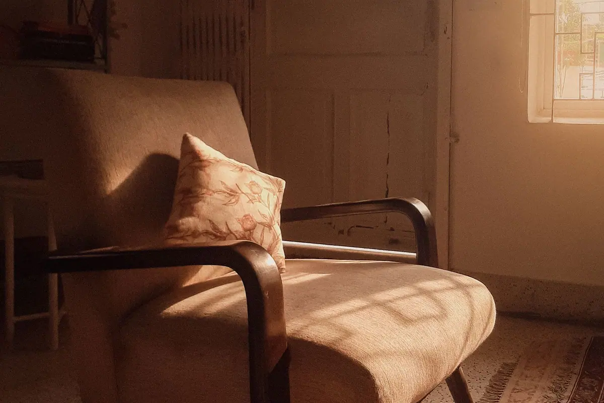 Un fauteuil près d'une fenêtre, dans une lumière chaude de fin d'après-midi